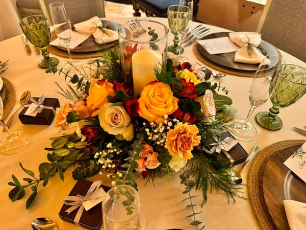 Centro de mesa alto con rosas naranjas y amarillas, gypsophila y follaje