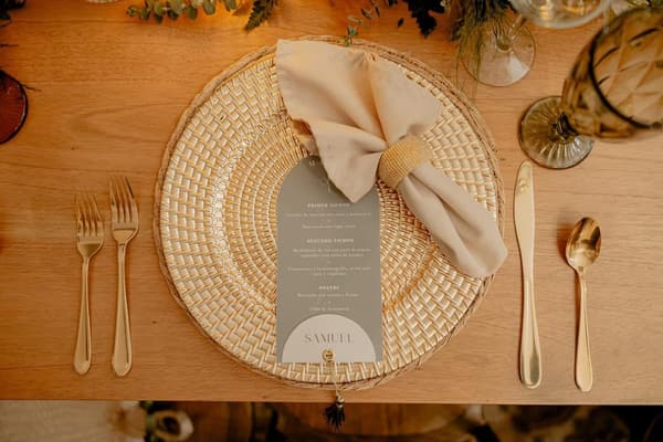 Puesto de mesa con plato de ratán tejido, servilleta anudada y menú individual