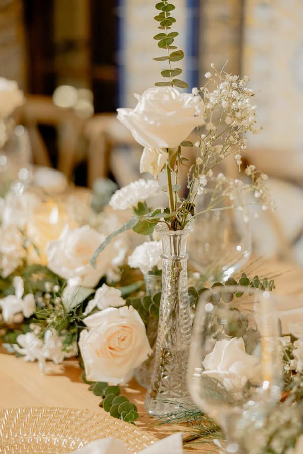 Rosas blancas y gypsophila en jarrón de vidrio sobre la mesa del banquete