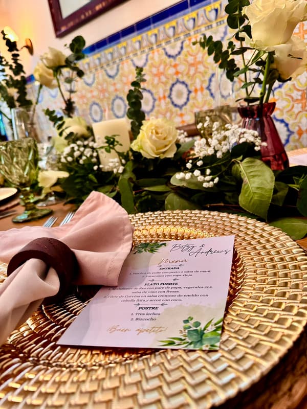 Puesto de mesa de boda con menú, servilleta rosada y flores amarillas